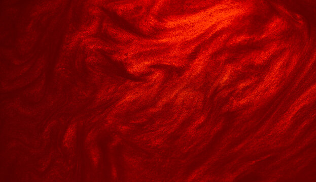 Shimmering red abstract background. Liquid glitter paint texture waves and swirls. Beautiful shiny red glitter texture. Metallic paint close-up as a holiday background.