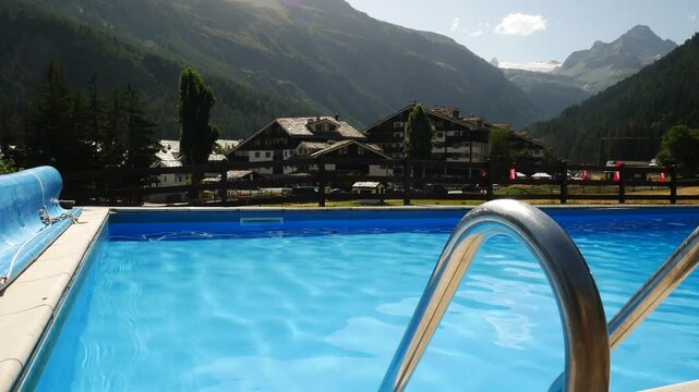 Swimming pool with blue calm waters in Aosta Valley, Italy. Italian alps and natural landscape with mountains on the background.