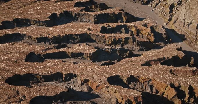 Aerial view showing the rugged terrain of Ambrym Island volcanic caldera, featuring deeply eroded channels and layered rock formations shaped by geological forces. Natural background