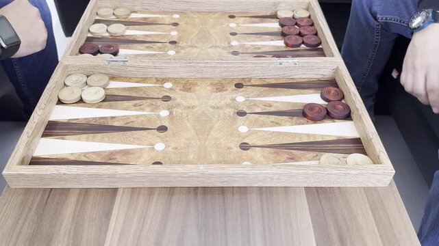 two people playing backgammon across the table