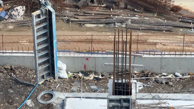 In a structure under shell construction, a reinforced concrete wall, a large steel shear wall formwork standing next to it, and column rebar waiting for pouring are visible.