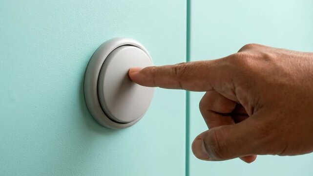 Finger pressing a doorbell button on a light blue wall