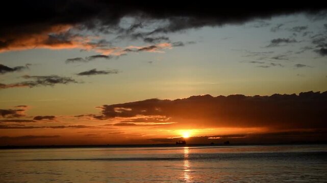 Stunning sunset at sea time lapse. Sun going down on the horizon with beautiful cloud movement. Blue and orange sky. Dramatic and cinematic sunset.