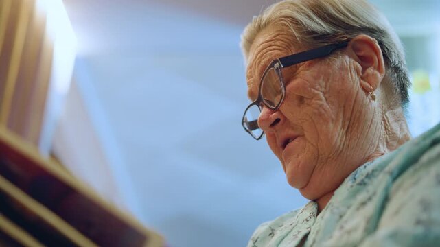 Closeup white grandma reading letter, soft kitchen light, vintage floral blouse, reading glasses perched, gentle expression, wrinkled hands holding envelope, nostalgic mood, warm sunlight