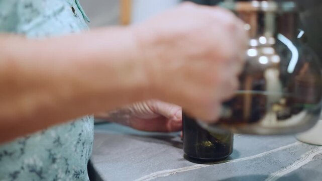 Grandma hands pouring coffee into mug, closeup aged hands stirring sugar at kitchen counter, green glass mug, glass kettle, sugar jar, warm morning light, domestic ritual, comforting atmosphere