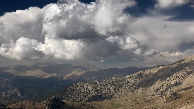 Panoramic cloudy view of Ethiopian mountains and highland valleys under dramatic sky. Broad vista reveals rugged peaks, rolling hills, shifting cumulus, Africa highlands in sunlight.