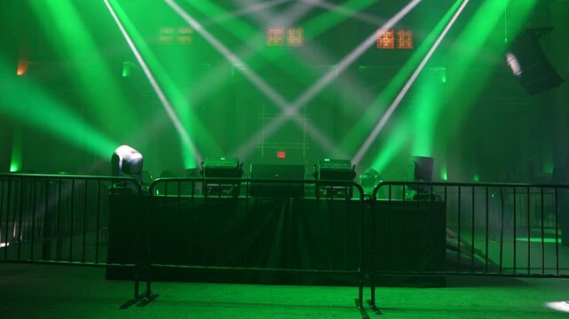 Bright green spotlights cut through the dark atmosphere of an empty stage or venue. The dynamic beams create circular patterns on the floor, evoking an energetic mood for a concert or live event.
