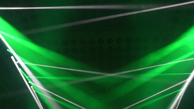 Bright green spotlights cut through the dark atmosphere of an empty stage or venue. The dynamic beams create circular patterns on the floor, evoking an energetic mood for a concert or live event.
