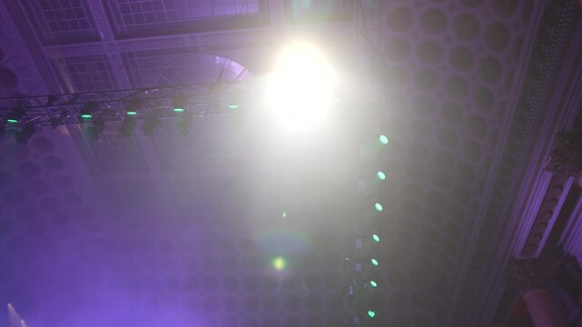Bright green spotlights cut through the dark atmosphere of an empty stage or venue. The dynamic beams create circular patterns on the floor, evoking an energetic mood for a concert or live event.
