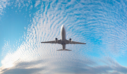 White passenger airplane flying in the sky amazing clouds in the background - Travel by air...