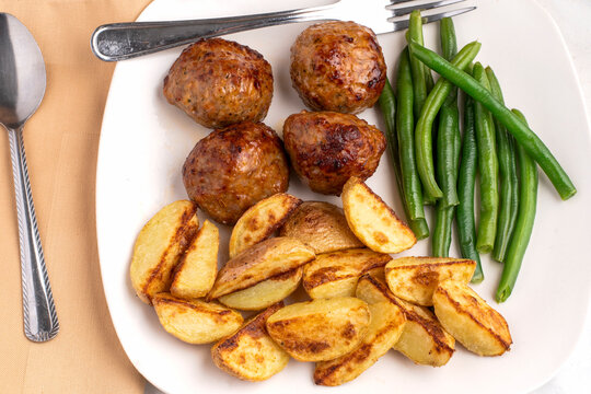  meat balls and potato wedges with green beans