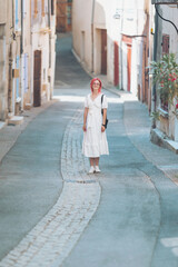 Obraz premium A traveler strolls through a picturesque alley in a quaint village in Provence, France. The charming white buildings and cobblestone paths create a dreamlike atmosphere perfect for exploration