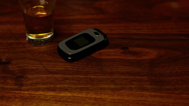 A young woman, distracted after drinking, slams down her beer and mistakenly picks up the wrong identical flip phone&mdash;highlighting impaired judgment, human error, and the consequences of alcohol.