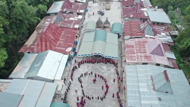 High angle drone footage of local people performing the traditional Reba dance in a circle within a tribal village in Bajawa, East Nusa Tenggara.
