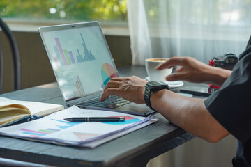 Obraz premium Close up of hands typing on laptop keyboard with business reports and coffee on desk.