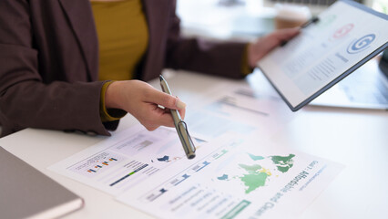 Adult business professional hand analyzing financial report data pointing document charts world map planning strategy corporate office work desk
