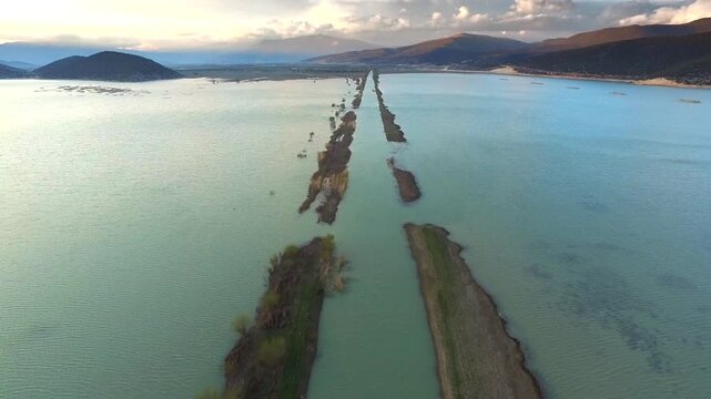 Drone aerial view shows catastrophic floodwaters submerging roads, homes, and settlements below. High angle deluge scene reveals inundated region, drowned infrastructure, plus widespread disaster.
