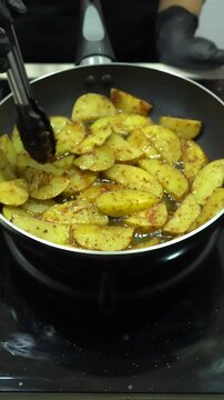 Chef Sizzling Seasoned Potato Wedges in Hot Frying Pan