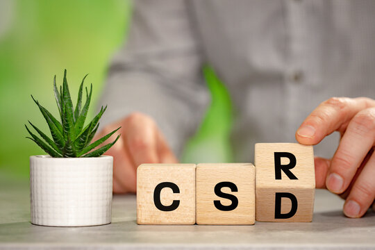 The businessman turns a wooden block with the symbol CSRD, Corporate Sustainability Reporting Directive. A business-environmental concept. Written on wooden blocks. Copy space