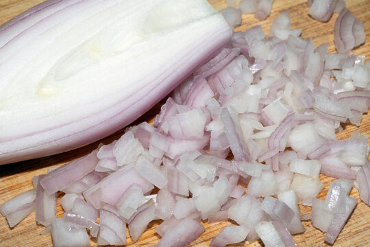 Close up of a chopped shallot onion on a wooden chopping board