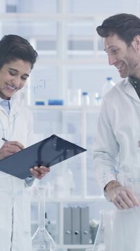 Talking, science or people with glass wall in lab, chemical compound experiment or medical research team. Formula board, cure discussion or scientist writing on clipboard, problem solving or smile