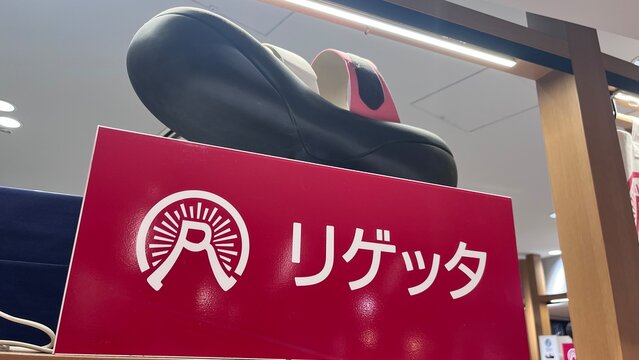 Urth Caffe display with a large black sandal on top of a red sign featuring the brand logo and name - Osaka, Japan, November 9, 2025