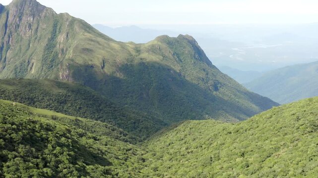 Expansive aerial view of lush green mountains and valleys filmed in motion