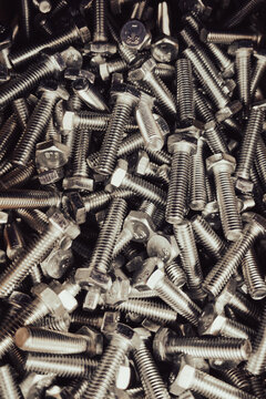 Stamped steel hex bolts in a dense disordered pile, grade markings visible on each head 