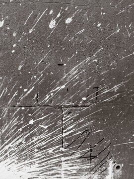 Textured gray surface covered with scattered white spray marks and paint trails