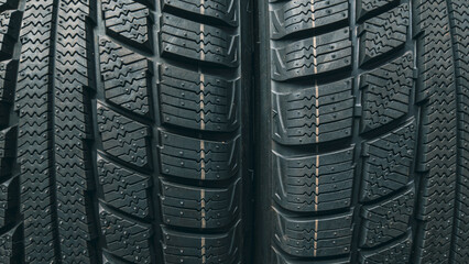 Two winter car tires side by side revealing complex directional tread block design up close © Дмитро Ганжеєв