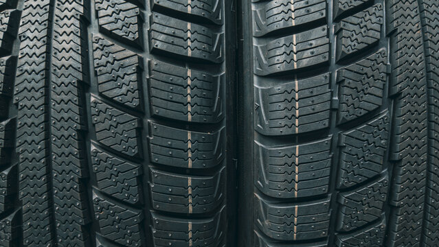 Two winter car tires side by side revealing complex directional tread block design up close