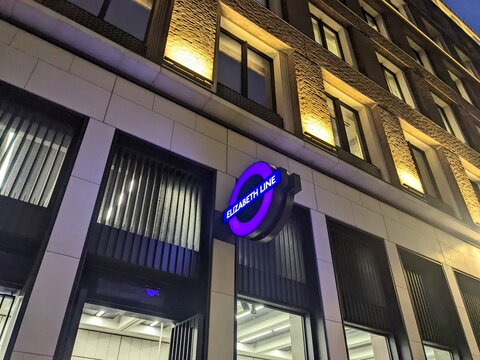Illuminated Elizabeth Line roundel sign at Bond Street station entrance in London after dark