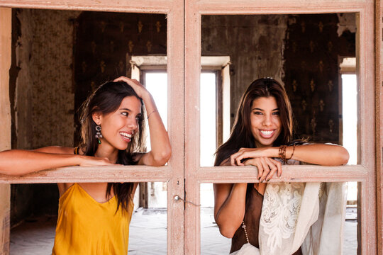 Two young women at rustic window


