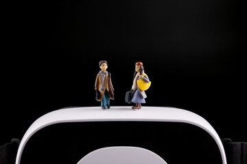 Fototapeta premium Miniature travelers on virtual reality headset with black background