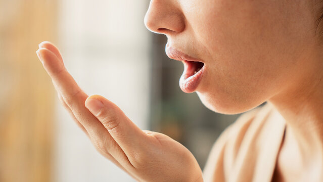 Woman is checking smell of breath