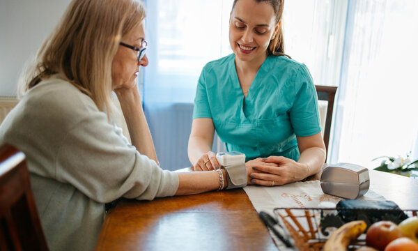 Doctor checks blood pressure of senior at home