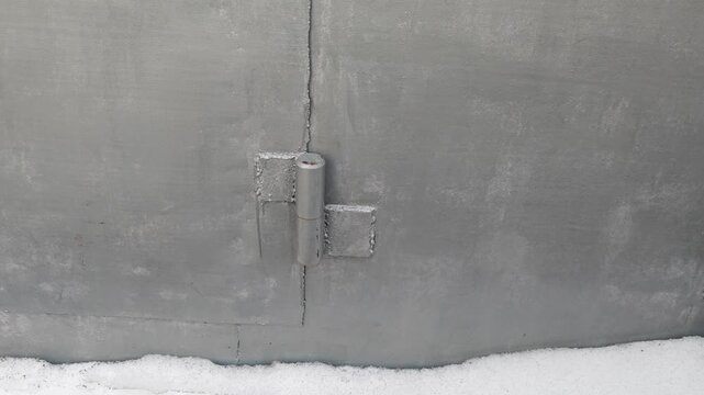 Close-up view of a metal hinge on a concrete wall, showcasing the gradual shift in angle and position across three sequential frames in a snowy environment