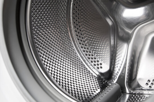 Washing machine revealing metal drum inside.