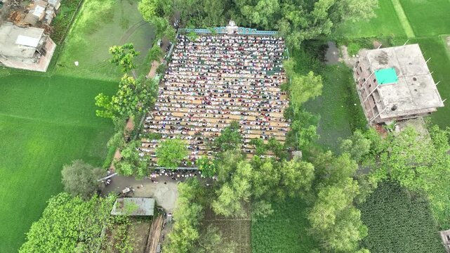 Aerial view of muslim community praying at eidgah surrounded by green fields