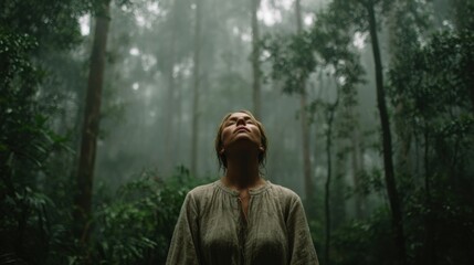 Obraz premium Woman Stands in an Ancient Forest With Arms Open and Eyes Closed, Surrounded by Mist and Tall Trees in a Moment of Mindfulness During Forest Bathing