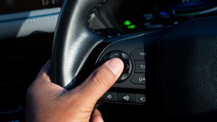 Obraz premium Silhouette intense light reflected on the driver hands as they pressed the buttons on steering wheel. Press finger on the center confirmation button. Feels confirm and clear of control.