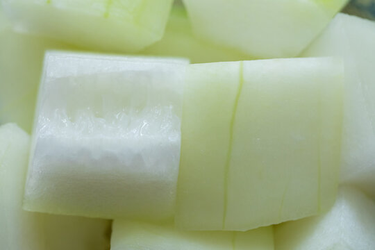 Close-up of sliced winter melon prepared for cooking, fresh cut pieces showing natural texture and pale green color
