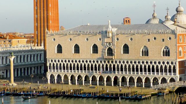 Iconic view of Doge&rsquo;s Palace with gondolas lined along the waterfront in Venice. Historic architecture and calm water reflections.
