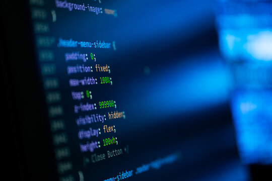 Close-up of glowing code on a dark screen.  Dark screen glows with code lines in blue and green hues