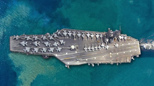 Aerial view of a naval aircraft carrier with fighter jets on deck in the Mediterranean Sea during military operations