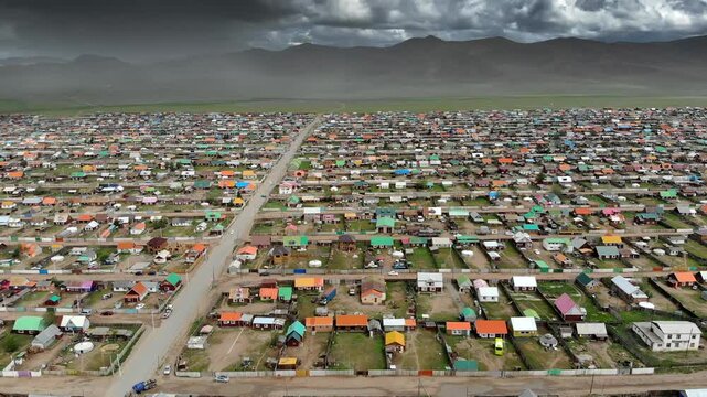 Urban housing districts in Mongolia captured by aerial drone over colorful city grid. High altitude flight reveals residential patterns, dense streets, and expanding settlements across open terrain.