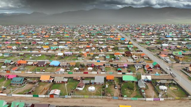 Urban housing districts in Mongolia captured by aerial drone over colorful city grid. High altitude flight reveals residential patterns, dense streets, and expanding settlements across open terrain.