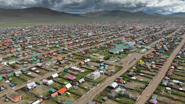 Urban housing districts in Mongolia captured by aerial drone over colorful city grid. High altitude flight reveals residential patterns, dense streets, and expanding settlements across open terrain.