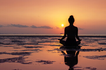 Yoga, Silhouette of woman meditating in lotus pose on beach at sunset, mindfulness and wellness concept