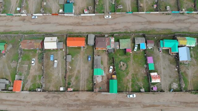 Urban housing districts in Mongolia captured by aerial drone over colorful city grid. High altitude flight reveals residential patterns, dense streets, and expanding settlements across open terrain.